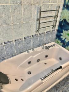 a white bath tub in a bathroom with tiles at Наш Дом in Adler