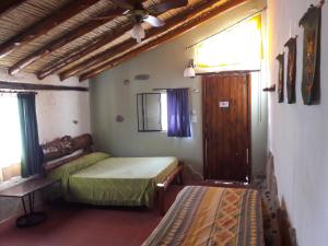 a room with two beds and a table and a window at Flor de las Sierras in Capilla del Monte