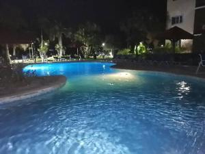 een groot zwembad van blauw water in de nacht bij Hermoso apartamento de playa en perla marina Sosua - Cabarete in Sosúa