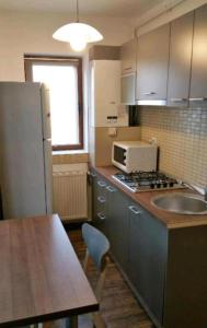 uma cozinha com um lavatório, um frigorífico e uma mesa em Apartament Aosta Central Sinaia em Sinaia