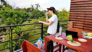 a young man drinking from a can on a balcony at BaanSuanklaiKlungBangkrachao บ้านสวนใกล้กรุงบางกะเจ้า in Phra Pradaeng