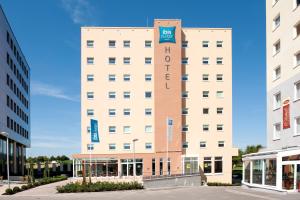 un gran edificio blanco con un cartel. en ibis Budget Luxembourg Sud en Livange