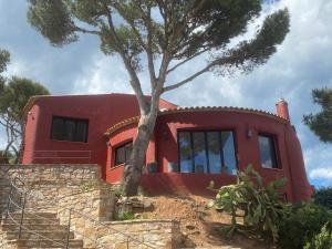 une maison rouge avec un arbre devant elle dans l'établissement Villa Gisele, à Tamariu