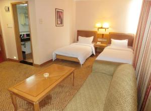 a hotel room with two beds and a couch at New Asia Hotel in Guangzhou