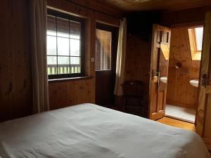 sypialnia z dużym łóżkiem i oknem w obiekcie Cosy Lakeside Chalet With Option to add Private Hot Tub & Boat w mieście Duneena