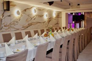 Długa jadalnia z białymi stołami i krzesłami w obiekcie Hotel Lazur SPA & Conference w Kaliszu