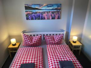 a bedroom with two beds with red and white checked pillows at Pension Ratsgasse in Weißensee