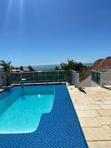 a blue swimming pool with the ocean in the background at Casa Lofstrom uma luxuosa com linda vista! in Tibau +21 photos