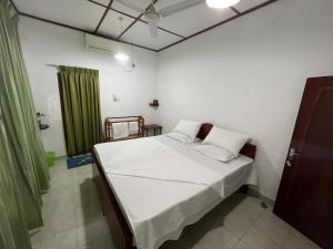 een kleine slaapkamer met een bed met witte lakens bij Summer Ridge - Homestay in Ratnapura