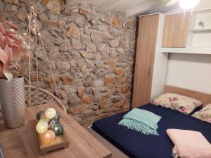 sypialnia z kamienną ścianą, łóżkiem i stołem w obiekcie Holiday House Pulina w mieście Punat +35 zdjęć