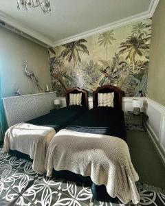 a bedroom with two beds and a mural of palm trees at De la Chambre au Jardin in Belleville-en-Beaujolais