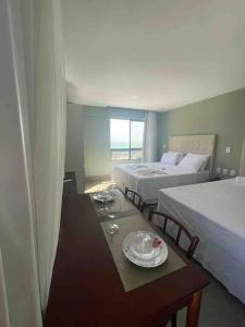 a hotel room with two beds and a table with plates on it at Ilusion flat Ponta Negra in Natal