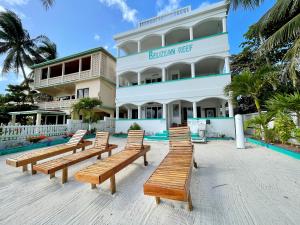 a row of wooden benches in front of a building at Belizean Reef Suites in San Pedro