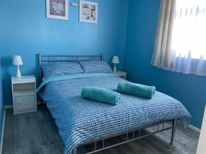 een blauwe slaapkamer met een bed met 2 kussens erop bij Driftwood WINTERTON VALLEY ESTATE Dog Friendly in Winterton-on-Sea