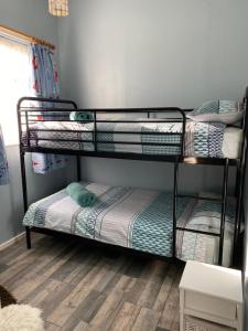 two bunk beds in a room with a wooden floor at Driftwood WINTERTON VALLEY ESTATE Dog Friendly in Winterton-on-Sea