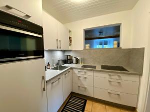 een keuken met witte kasten en een zwart apparaat bij Ferienwohnung an der idyllischen Salzachschleife Nähe Salzburg in Laufen