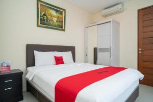 a bedroom with a large bed with a red blanket at RedDoorz near ITDC Nusa Dua in Nusa Dua
