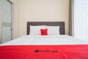 a bed with a red pillow on top of it at RedDoorz near ITDC Nusa Dua in Nusa Dua