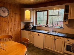 a kitchen with a table and a clock on the wall at Cosy Lakeside Chalet With Option to add Private Hot Tub & Boat in Duneena