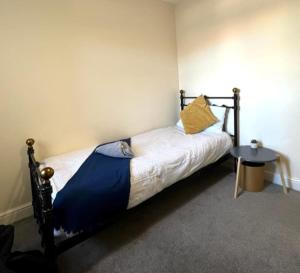 a bed with a blue blanket and a table in a room at Short term lets from £15 per person per night in Bristol