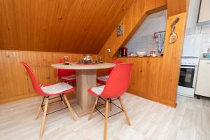 a kitchen with a table and four red chairs at Studio Apartman Poljančić in Ravna Gora