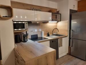 cocina con encimera de madera y nevera en La Petite Foret Chamrousse 1700, en Chamrousse