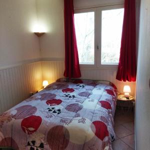een slaapkamer met een bed en een raam met rode gordijnen bij appartement du pecheur in Valras-Plage