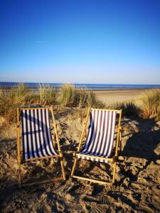two chairs sitting in the sand on the beach at Zeester en koffie. in Oostduinkerke-Bad