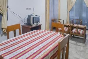 ein Schlafzimmer mit einem Bett und einem TV auf einem Tisch in der Unterkunft Mataram Cottage Syariah Mitra RedDoorz in Pasakon 1