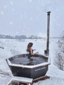 a girl sitting in a bath tub in the snow at Woody Village Riverside in Panteleyevo