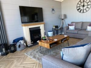 ein Wohnzimmer mit einem Sofa, einem Tisch und einem Kamin in der Unterkunft Padstow Lodge - Padstow Holiday Village in Padstow