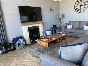 un salon avec un canapé, une table et une cheminée dans l'établissement Padstow Lodge - Padstow Holiday Village, à Padstow