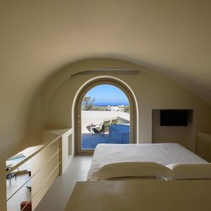 a bedroom with a bed and a view of the ocean at Santopaz Suites in Oia