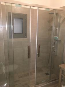 a shower with a glass door with a tv on the wall at Καμάρα Χωριό Φοινίκι , Kamara Finiki Village in Moláoi