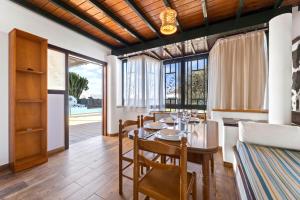 comedor con mesa, sillas y ventanas en Villa Lele, en Playa Blanca
