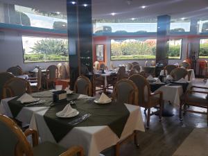 a dining room with tables and chairs and windows at Hotel Alcampo in Querétaro