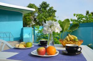 einen Tisch mit Obstteller, Tassen und einer Vase Blumen in der Unterkunft Velaa Garden View, Fodhdhoo- Maldives in Fodhdhoo