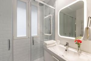 ein weißes Badezimmer mit Waschbecken und Spiegel in der Unterkunft Waou Chamberi V - Alquiler Corta Duración in Madrid