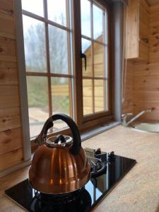 a tea kettle sitting on top of a stove in a kitchen at Beautiful Wooden tiny house, Glamping cabin with hot tub 2 in Tuxford