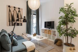 ein Wohnzimmer mit einem blauen Sofa und einem Fernseher in der Unterkunft Waou Chamberi V - Alquiler Corta Duración in Madrid