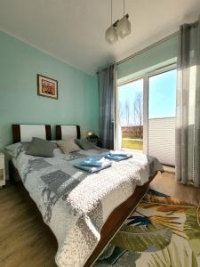 a bedroom with a large bed and a large window at Apartament Laurowy in Darłowo