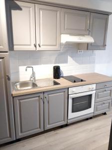 a kitchen with white cabinets and a sink at Studio Lou Cigaloun climatisé in Gréoux-les-Bains +6 photos