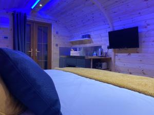 a bedroom with a bed and a flat screen tv at Bryn Glamping in Coychurch