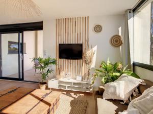 sala de estar con TV de pantalla plana y plantas en ** Superbe appartement sur le canal du midi **, en Laredorte