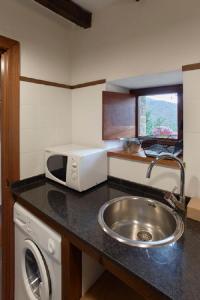 eine Küche mit einer Spüle und einer Mikrowelle in der Unterkunft Casa de Aldea Casa de Rubio in Linares
