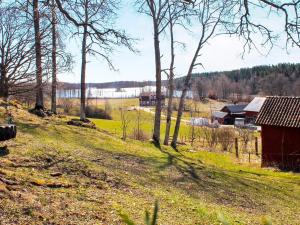 un campo con un granero rojo en una colina con árboles en Holiday home STJÄRNHOV, en Stjärnhov