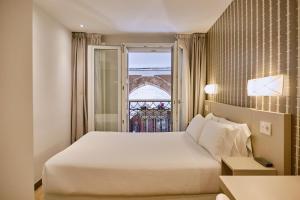 una camera d'albergo con letto e finestra di Hostal Suso a Santiago de Compostela