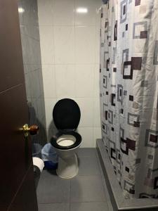 ein Bad mit einem schwarzen WC und einem Duschvorhang in der Unterkunft Casa amplia cerca del cc Titan Plaza in Bogotá