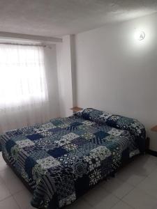 ein Schlafzimmer mit einem Bett mit einer blau-weißen Decke in der Unterkunft Casa amplia cerca del cc Titan Plaza in Bogotá