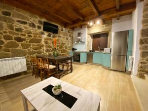 a large kitchen with a table and a refrigerator at Casa do Veiga in Chantada